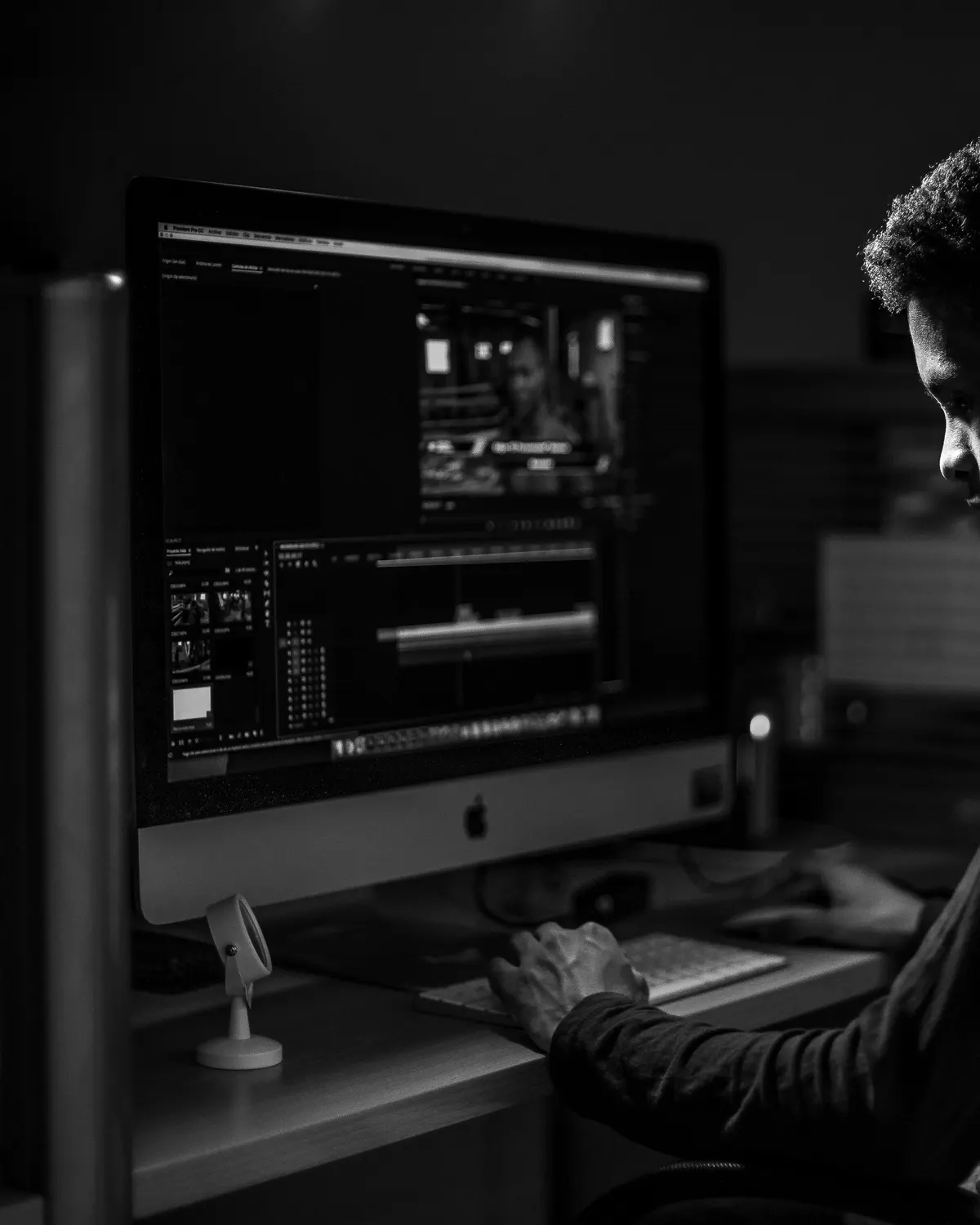 Persona editando frente a varias pantallas, en blanco y negro